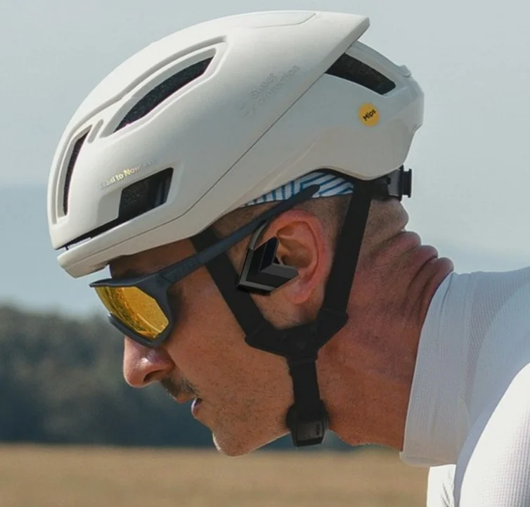 A road cyclist in a white helmet wearing the Vensono accessory at the ear